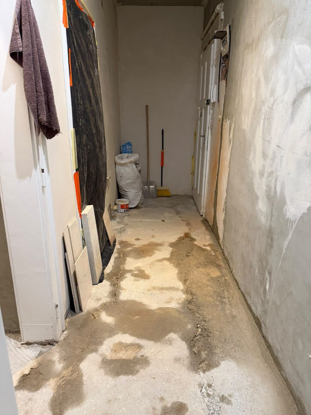 Chodba během rekonstrukce s hrubou betonovou podlahou, neomítnutými stěnami a stavebním materiálem